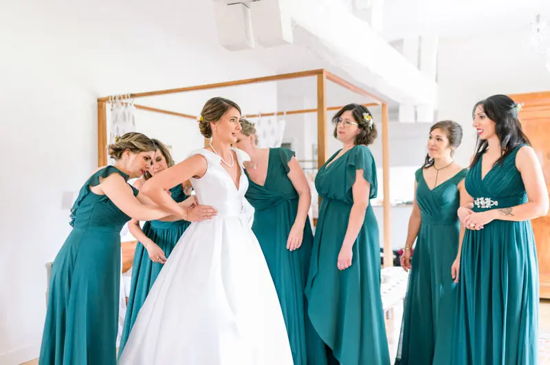 Bride hugging her bridesmaids in emerald green dresses