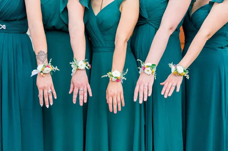 Bridesmaids in green dresses showing their floral wrist corsages