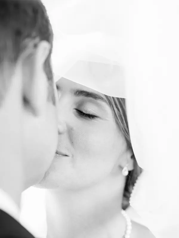 Close-up of the couple's kiss, veil drifting, in black and white