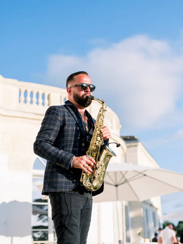 Saxophonist in a checked jacket playing during the outdoor cocktail hour