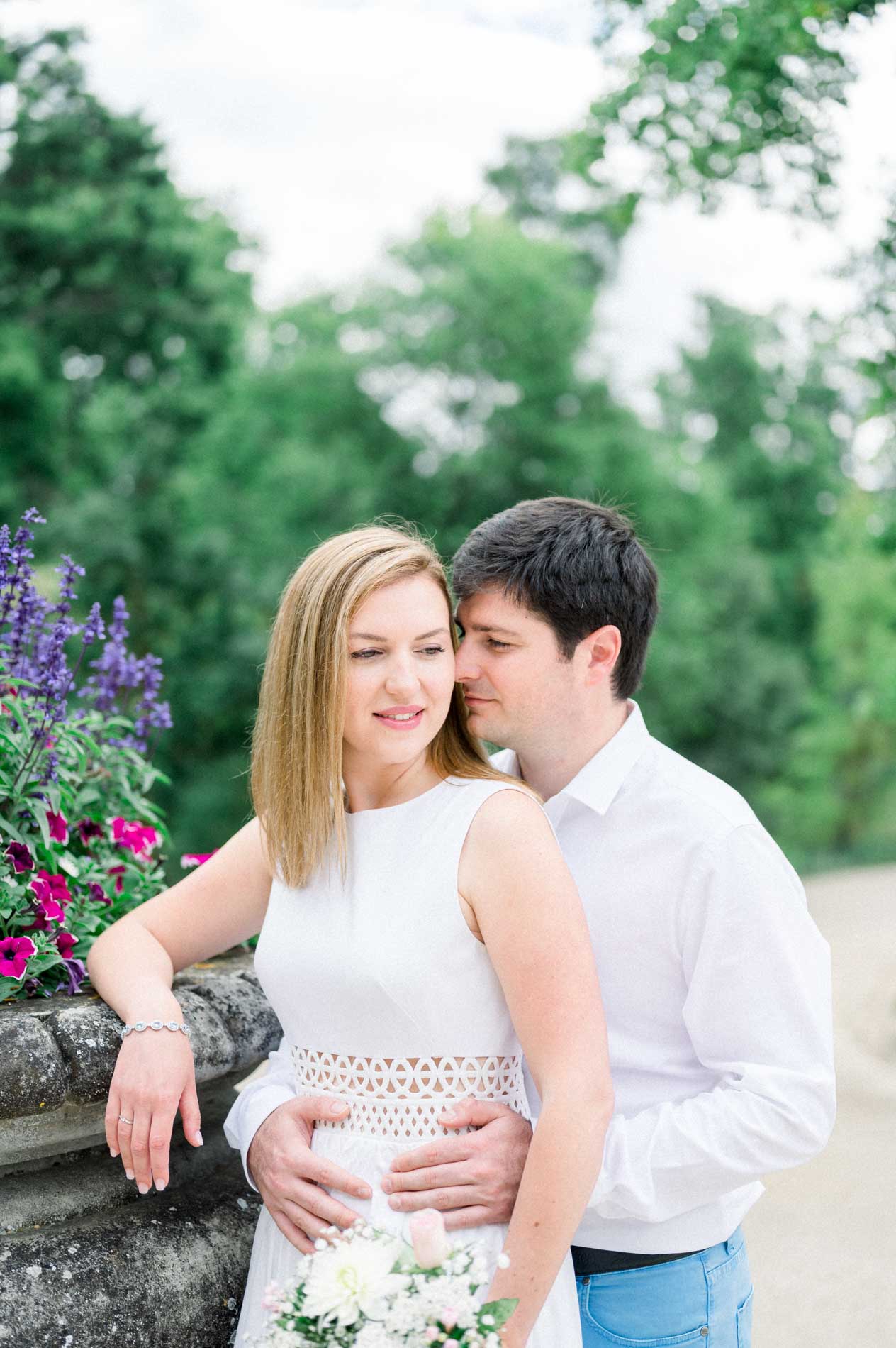Nicolas holding Tamara close beside a flower-filled urn