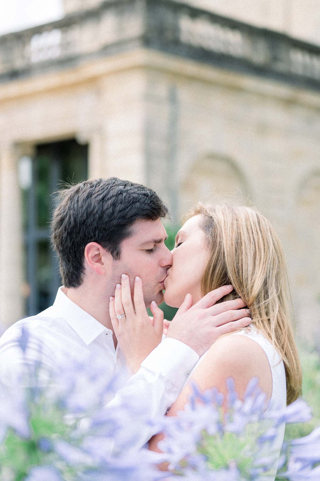 Tamara and Nicolas kissing behind agapanthus flowers