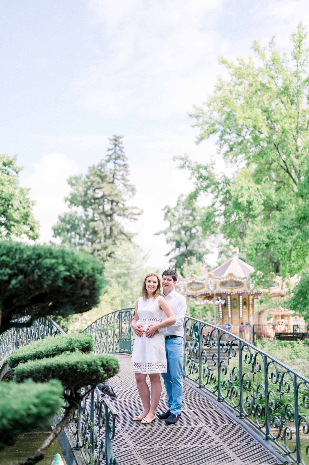 Tamara and Nicolas on a footbridge with the Jardin Public carousel behind them