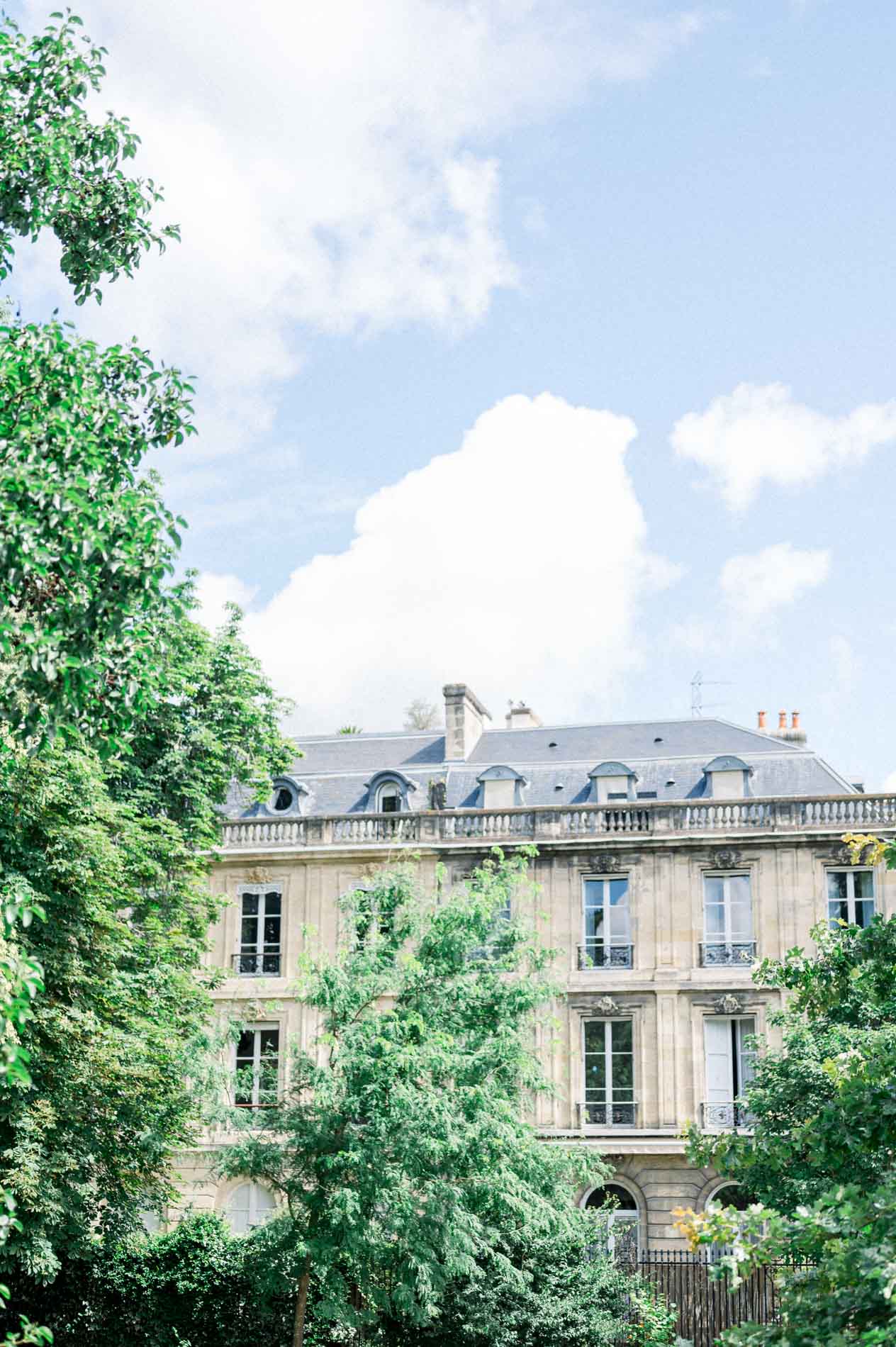 Façade of a Bordeaux building rising above the trees of the Jardin Public