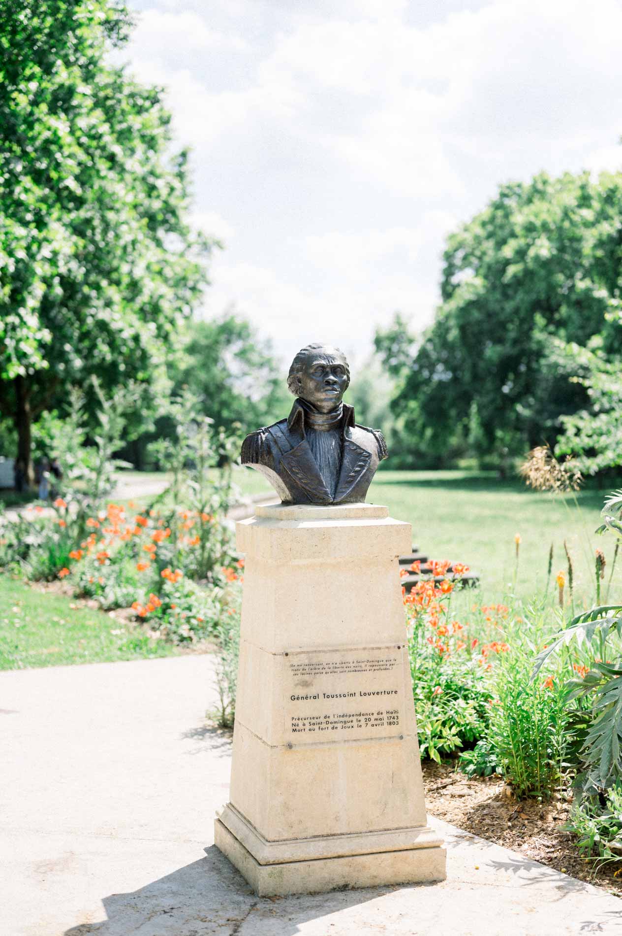 Bronze bust on a stone plinth along a path in the botanical garden