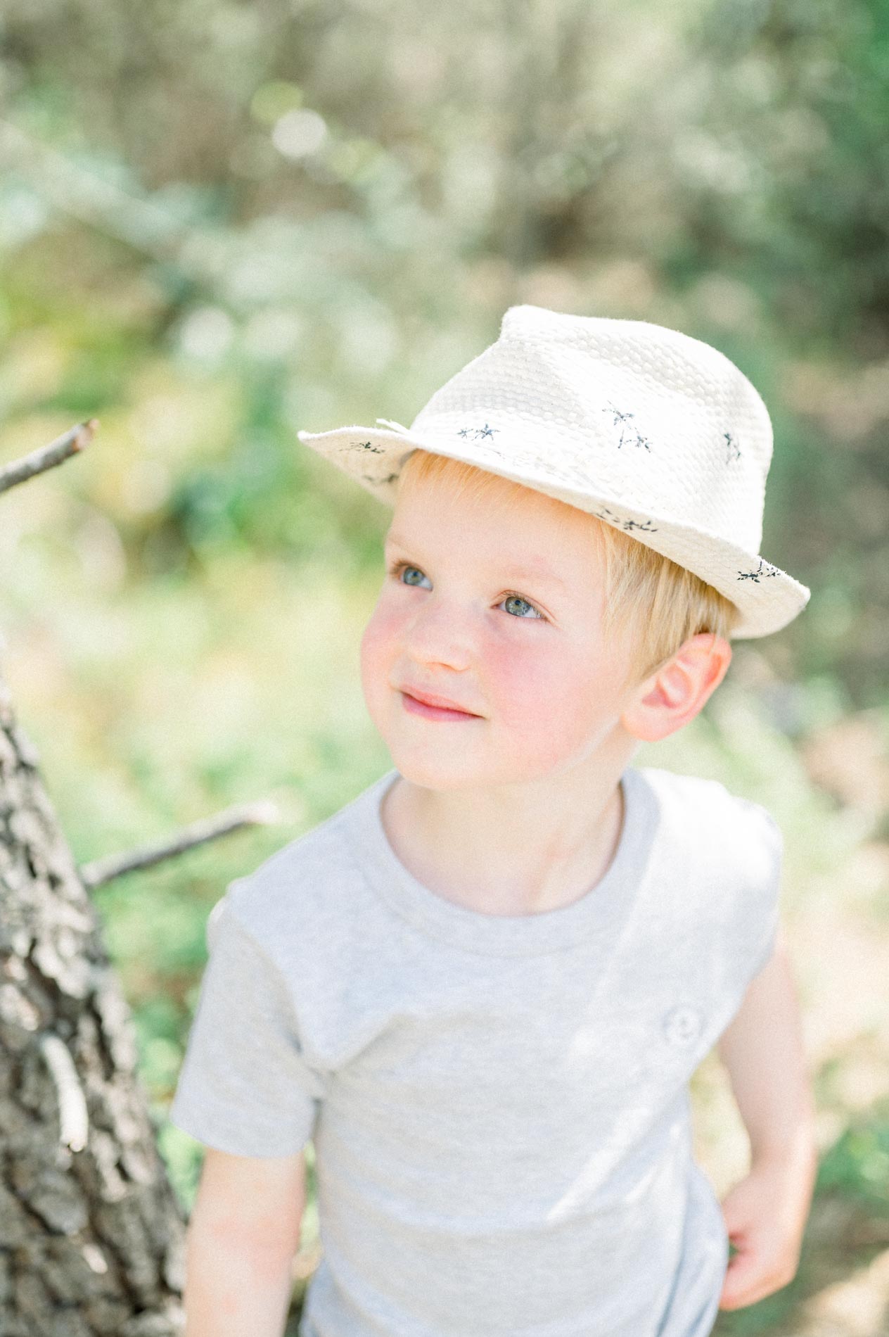 Portrait of the little boy in a straw hat with rosy cheeks