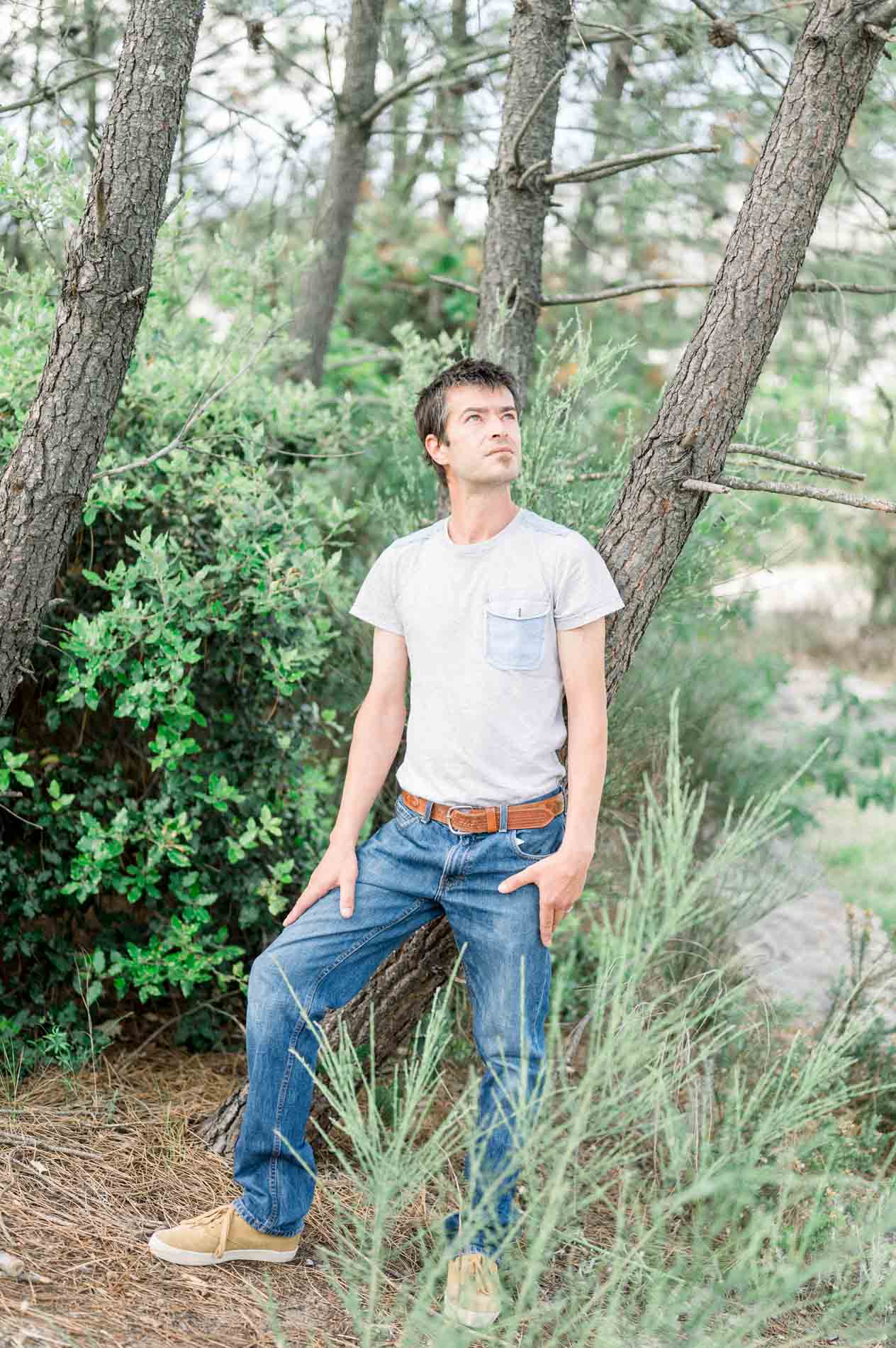 The dad in jeans and a grey T-shirt standing among the pines