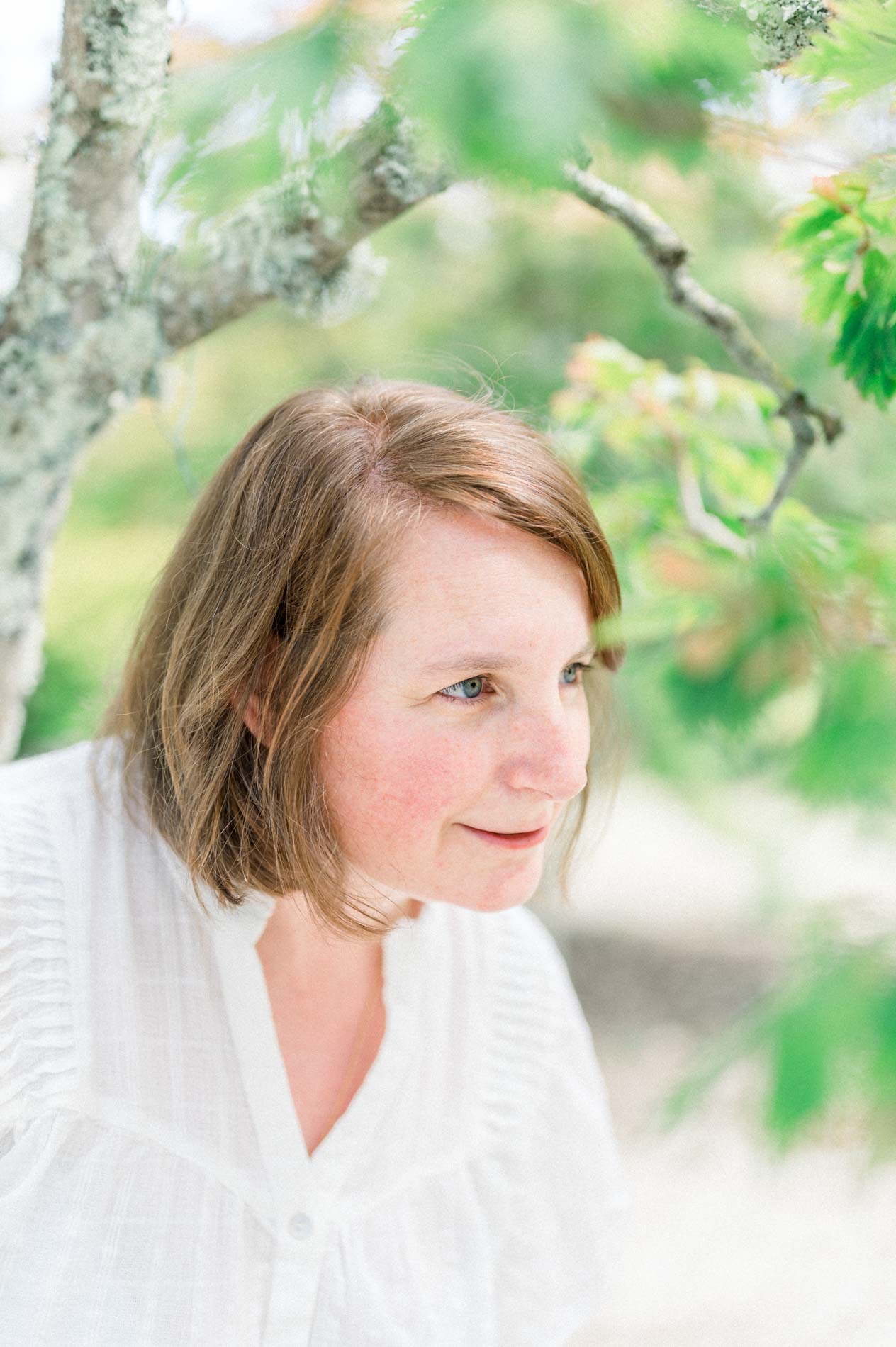 Portrait of the smiling mum beneath the branches at the botanical garden