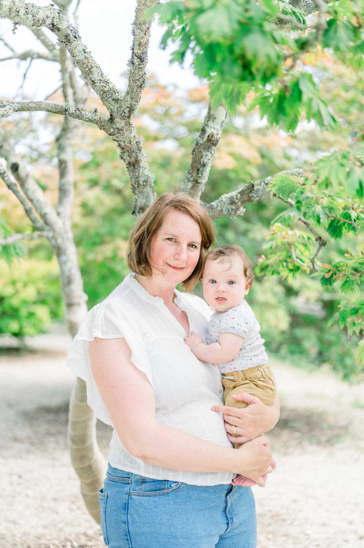 The mum holding her baby in her arms beneath the trees