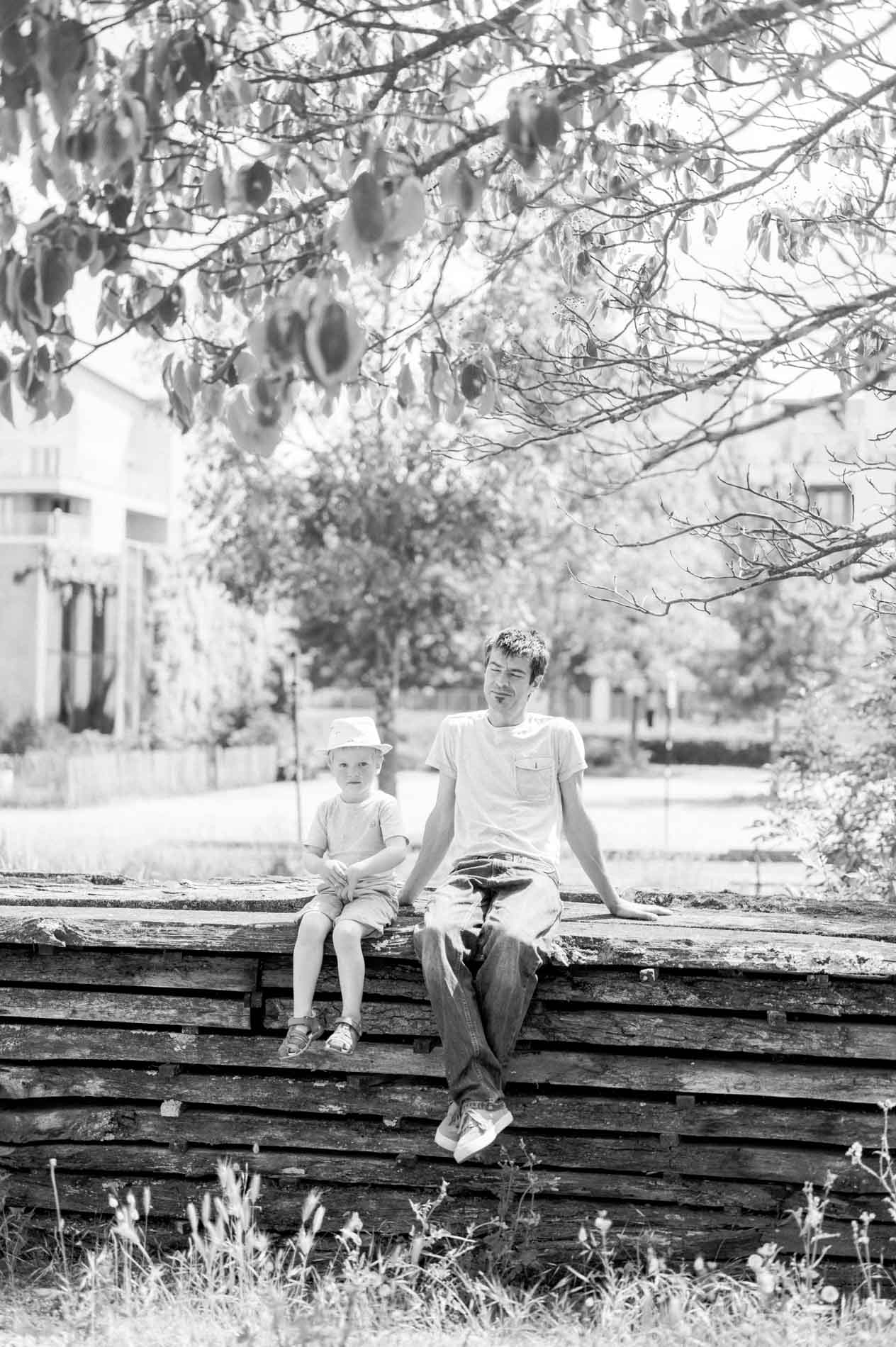 A dad and his son sitting on wooden sleepers, in black and white
