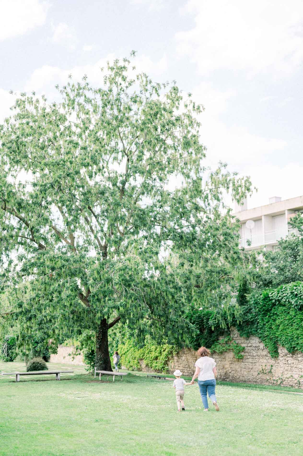 The mum and her son walking across the lawn beneath a large tree