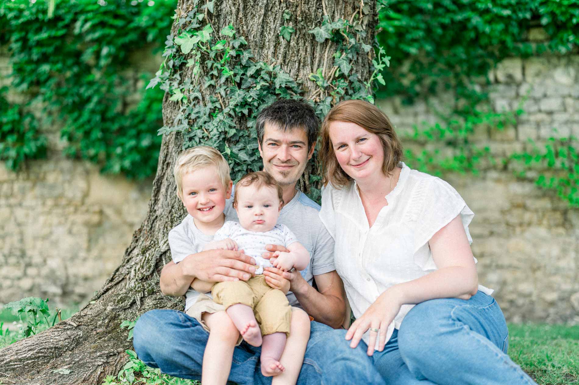Parents and their two young children sitting beneath a tree in the botanical garden