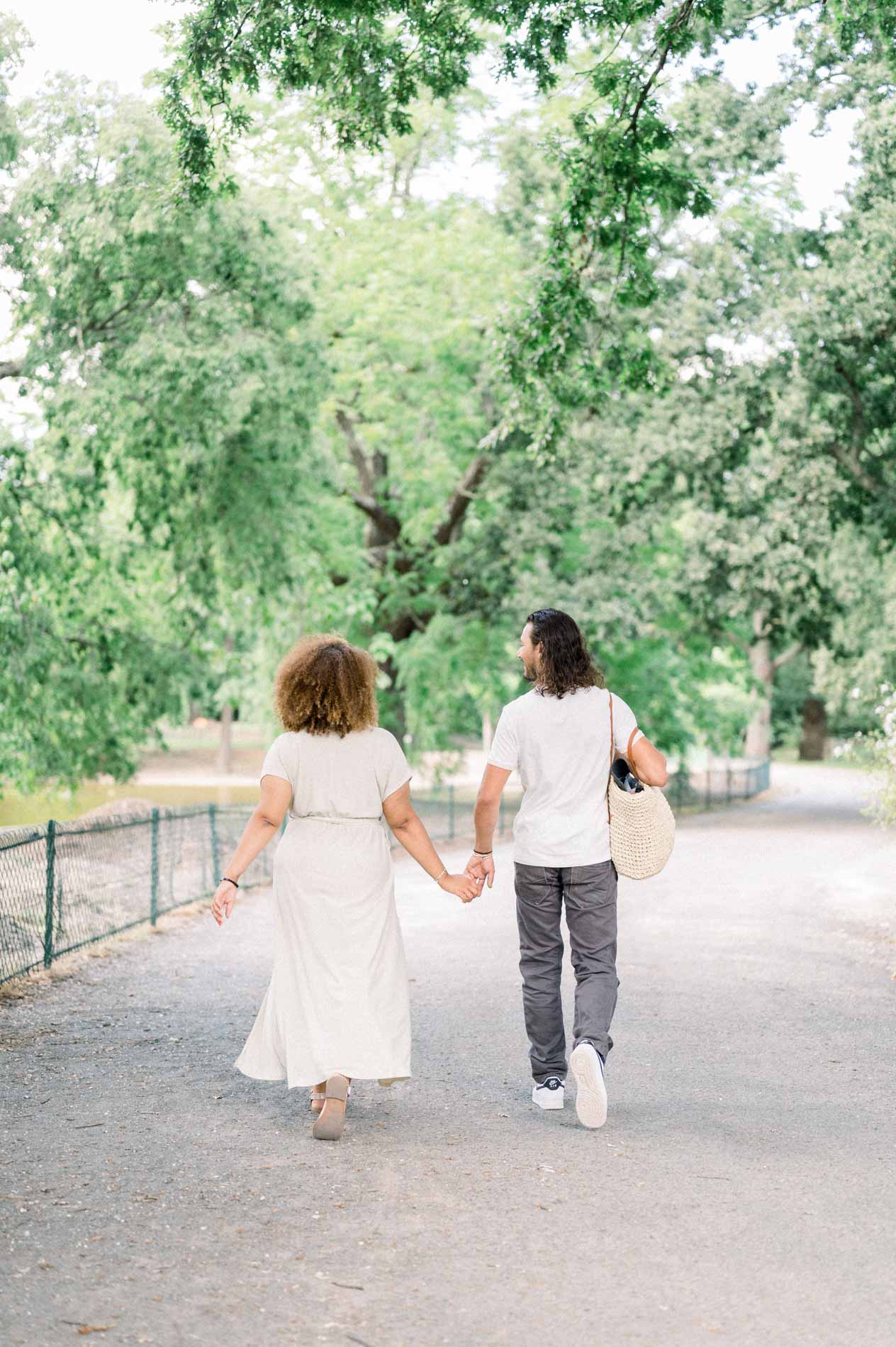 Couple seen from behind walking hand in hand along a park path
