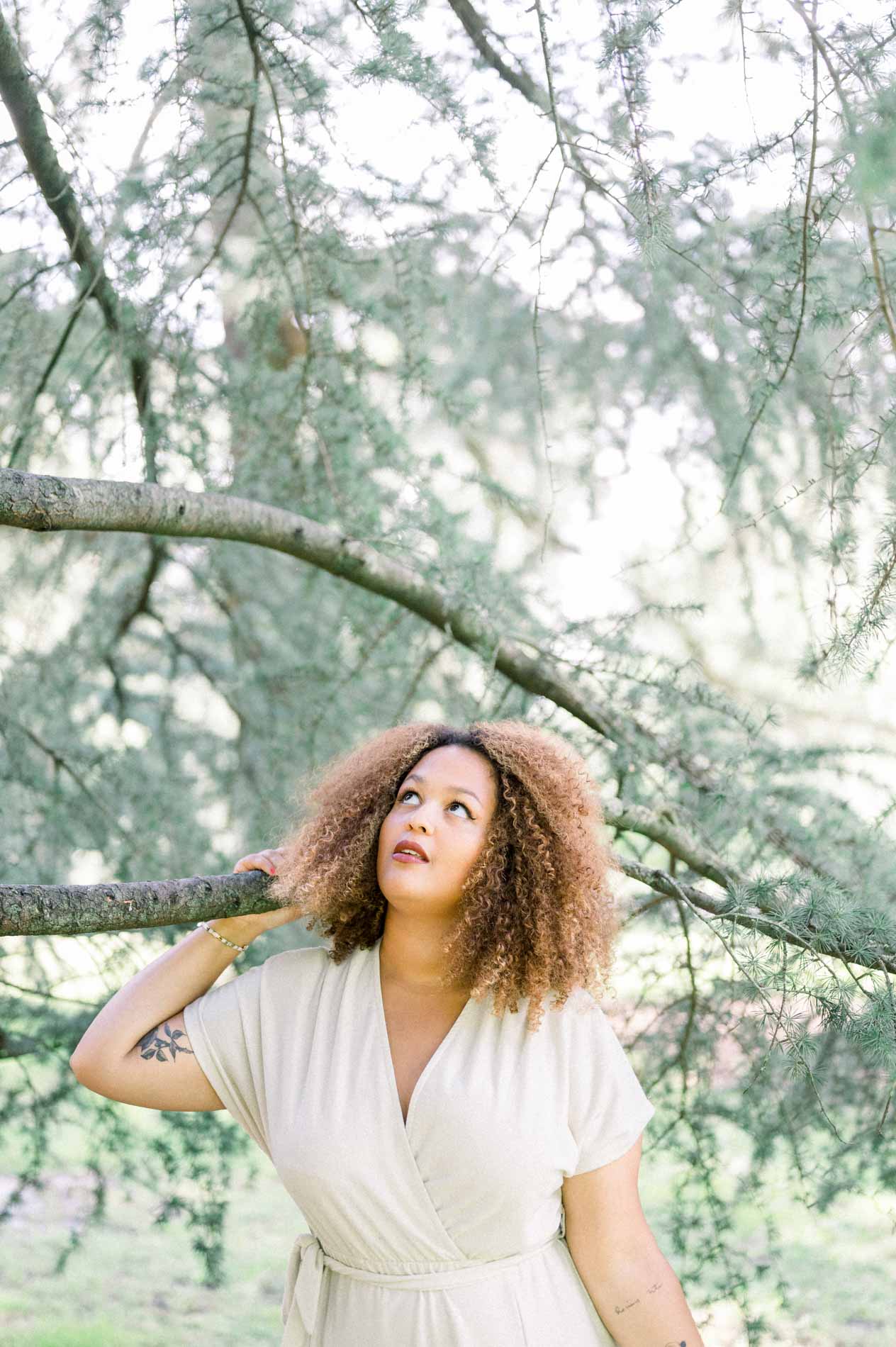 Young woman looking up at the sky beneath cedar branches