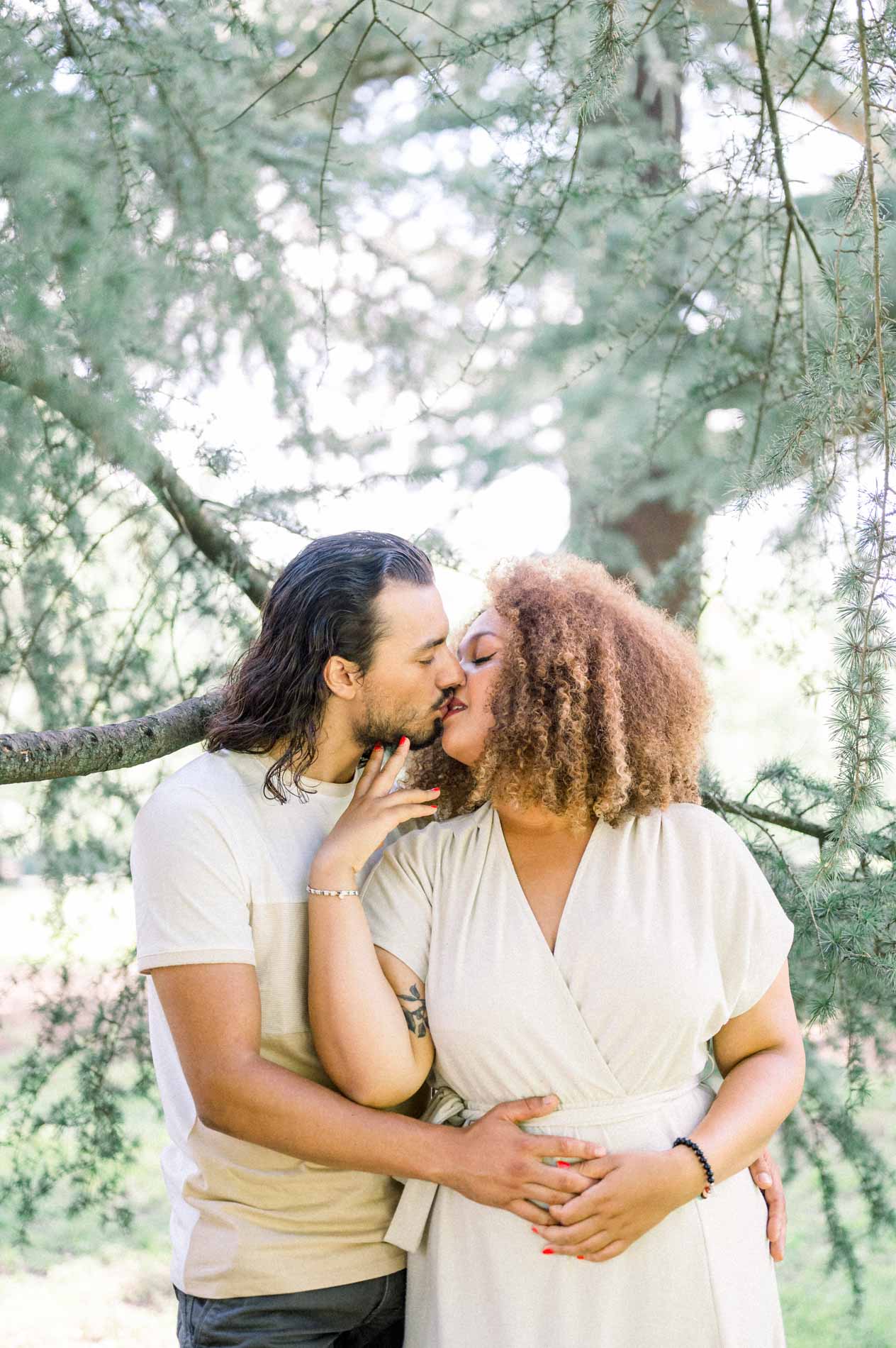 Kiss on the cheek beneath the low branches of a cedar