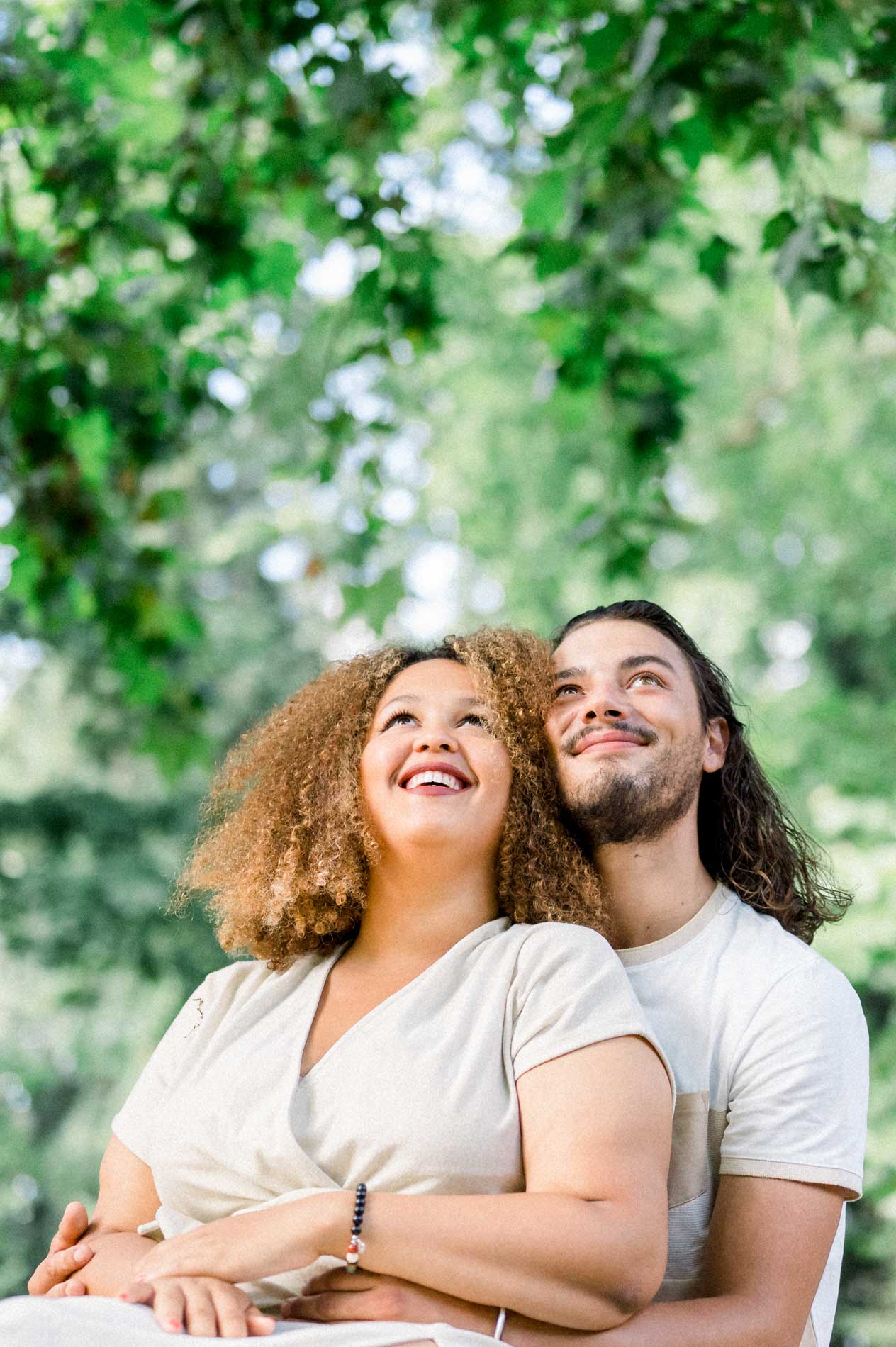 Couple embracing and looking up at the park's trees