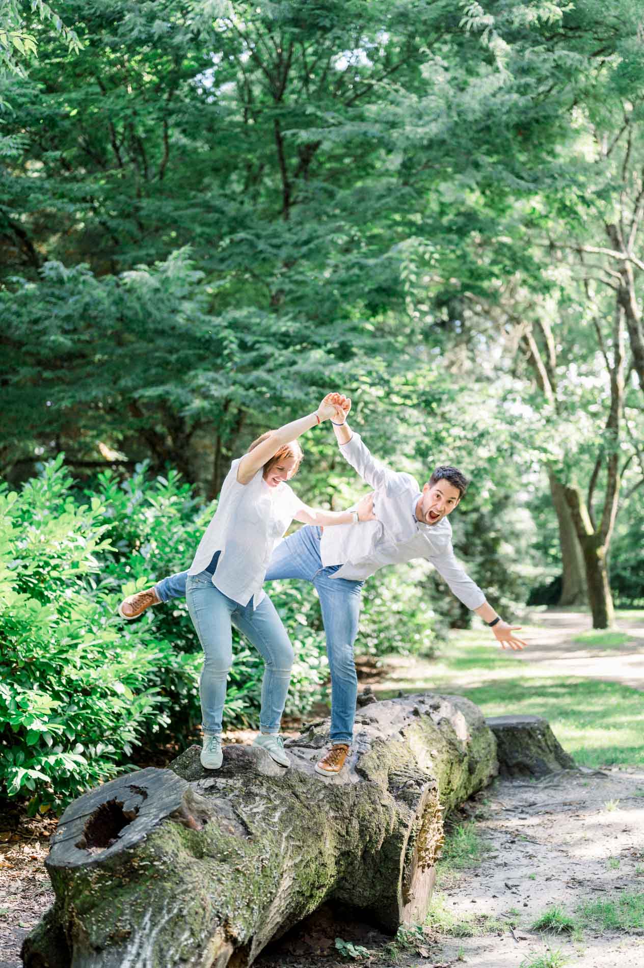 Parents-to-be playfully balancing on a tree trunk in the Parc Bordelais