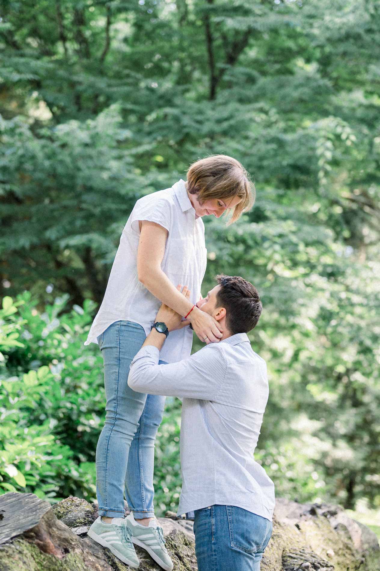 Mother-to-be on a log with her partner holding her waist