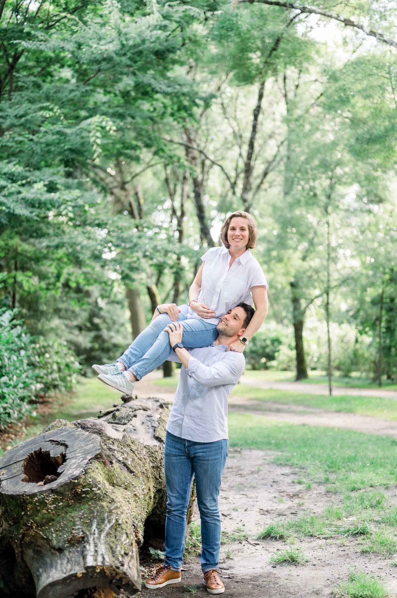Mother-to-be sitting on a hollow log with her partner beside her