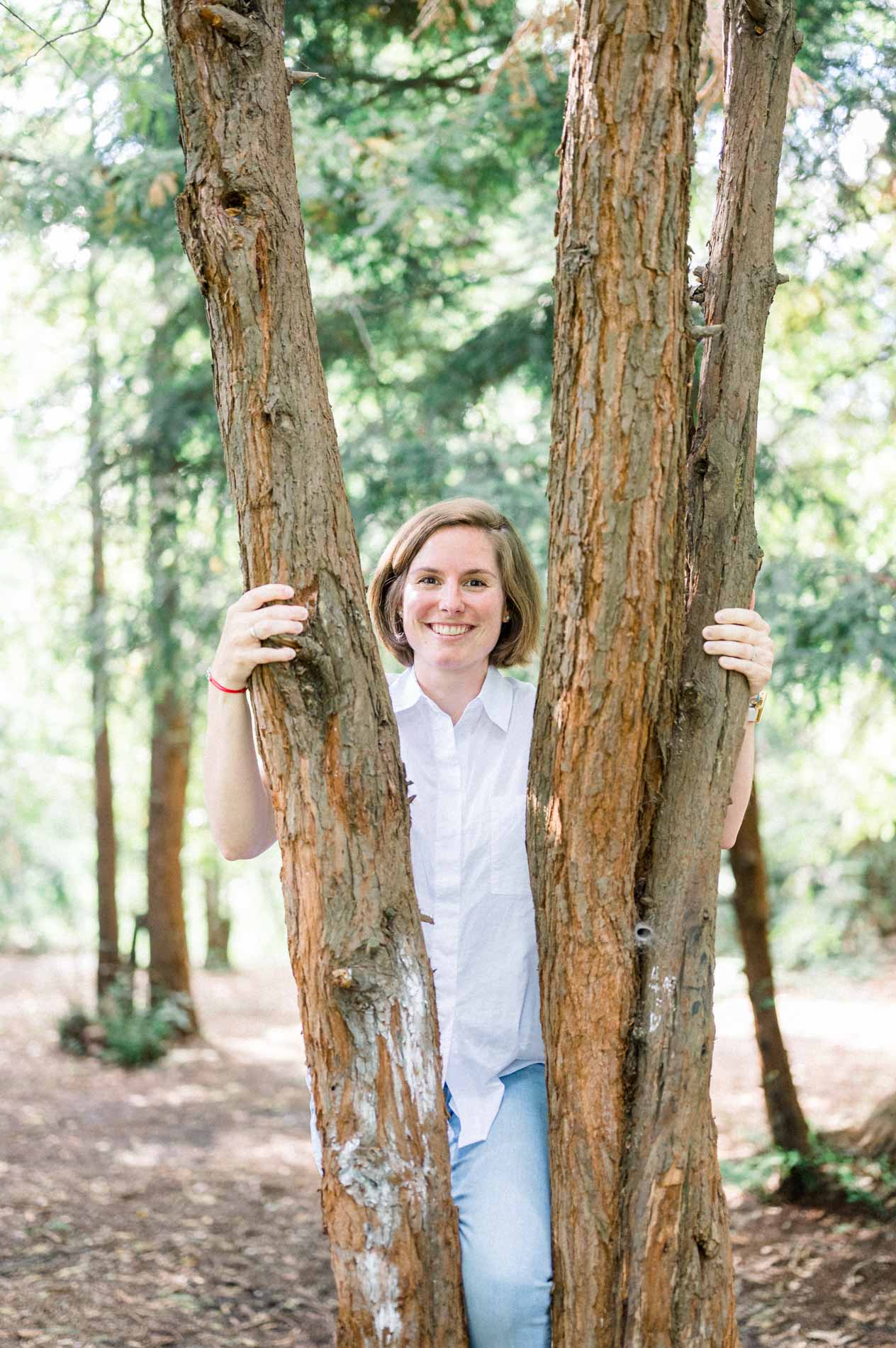 Smiling mother-to-be standing between two tree trunks