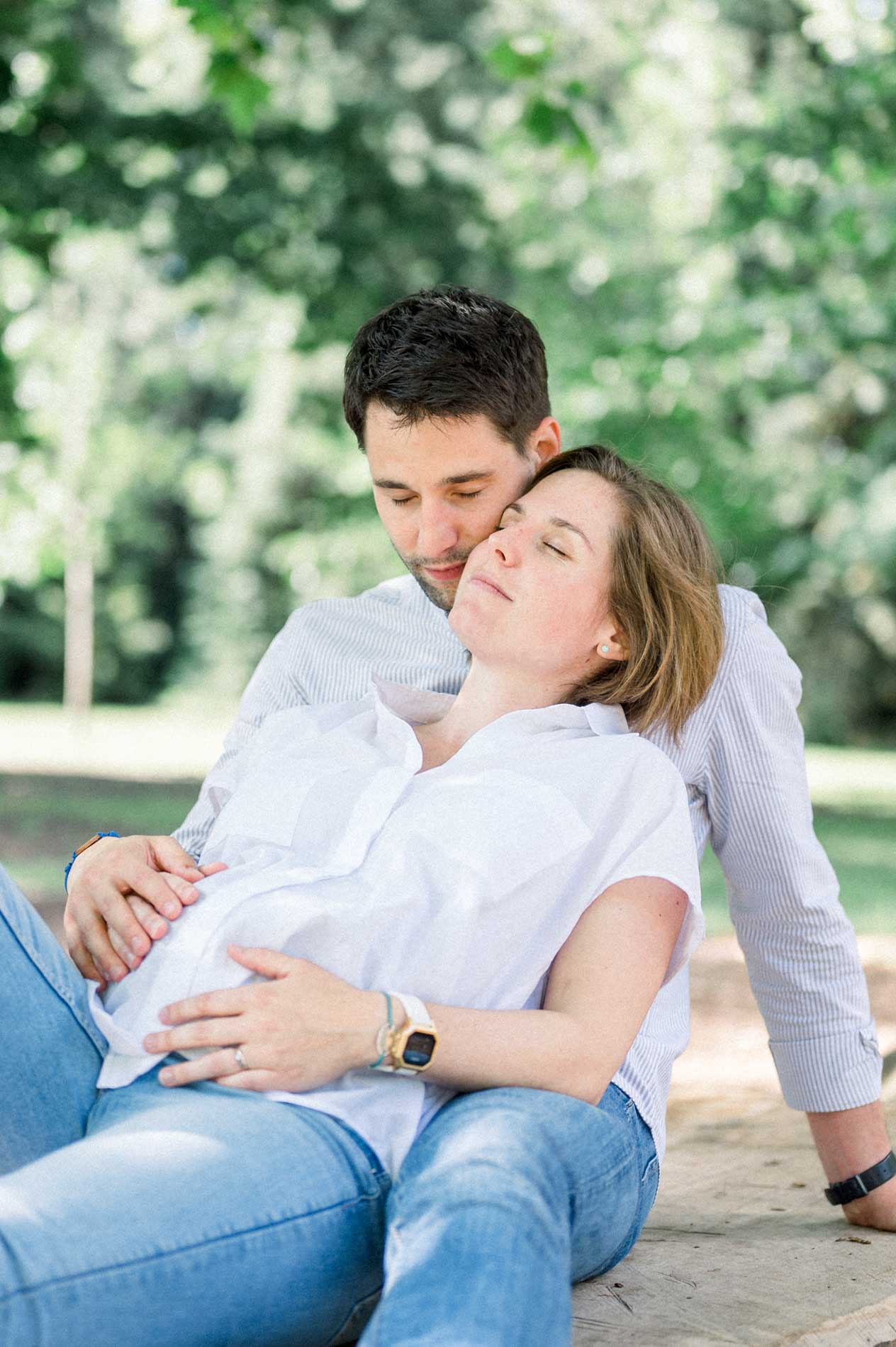 Mother-to-be nestled against her partner, hands on her round belly
