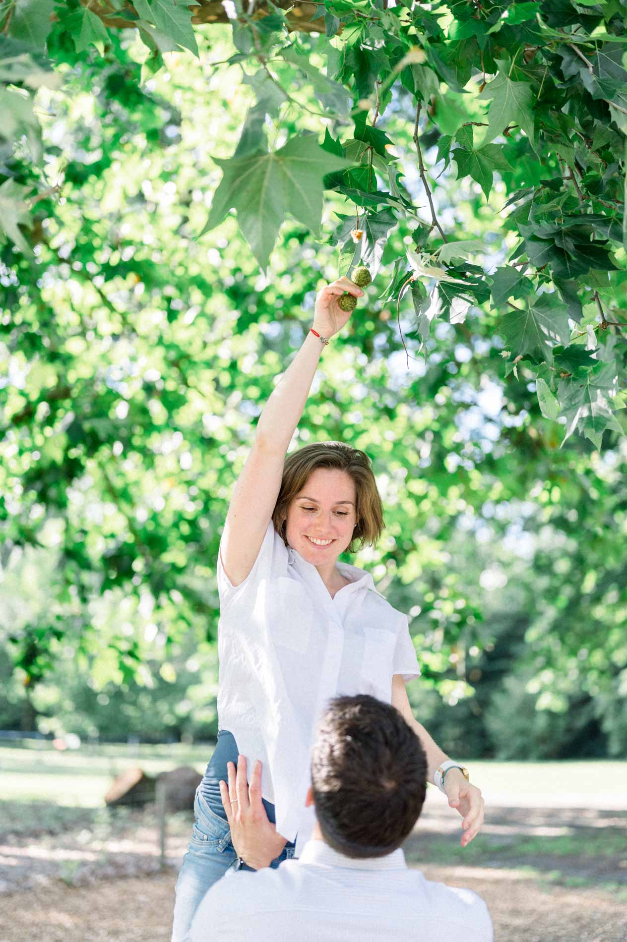 Mother-to-be picking a leaf as her partner looks up at her