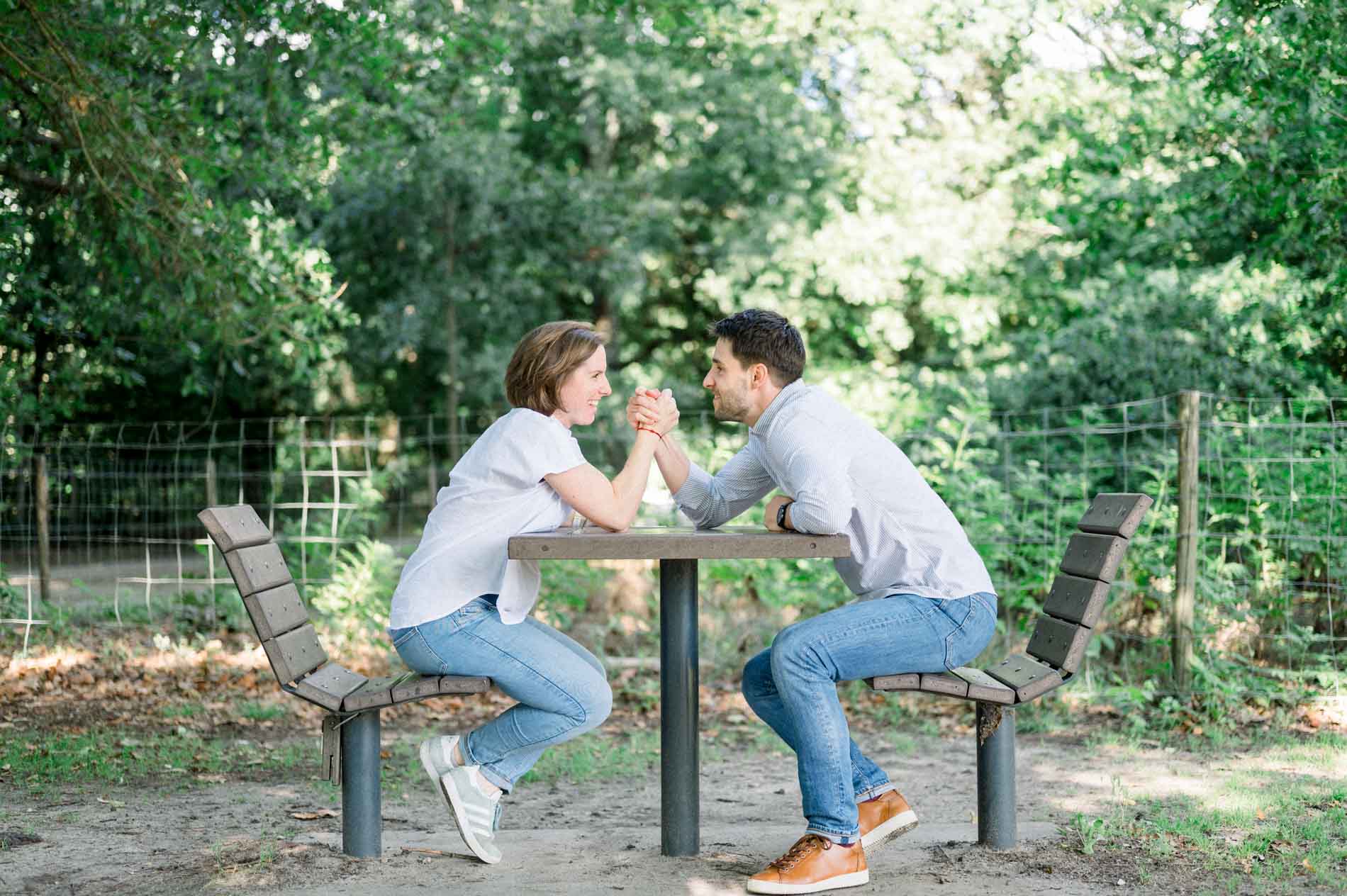 Parents-to-be arm wrestling at a picnic table
