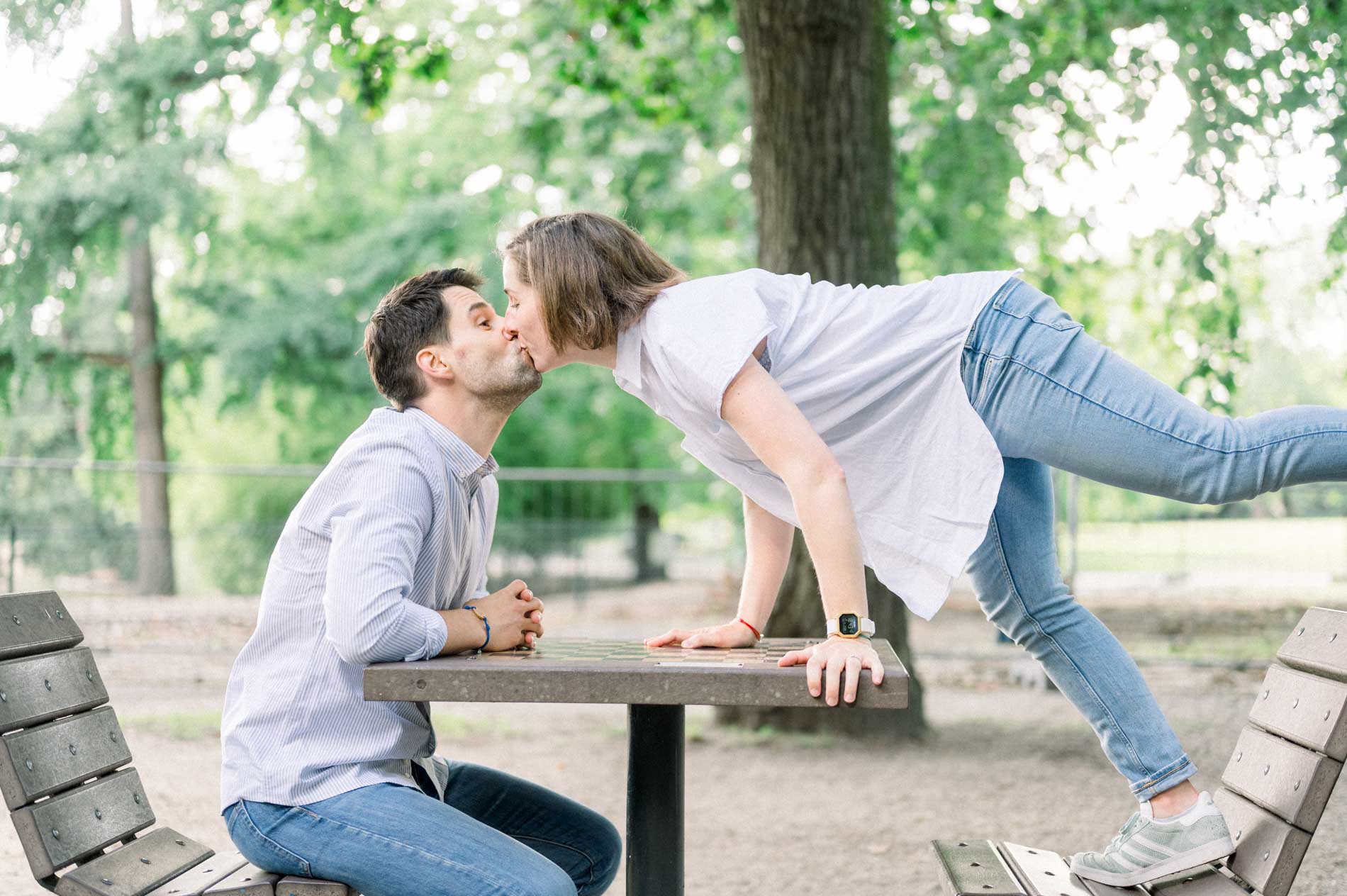Couple kissing across a picnic table during a lifestyle maternity session in Bordeaux