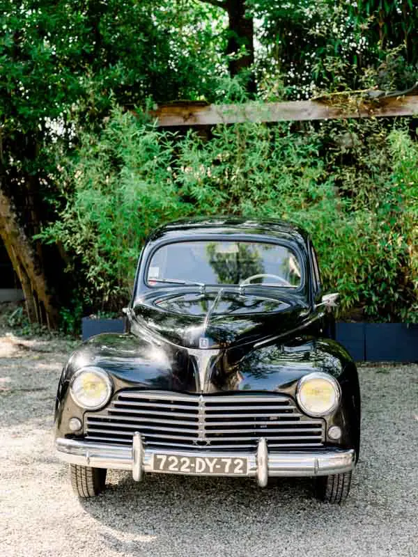 The couple's black vintage car parked beneath the trees at Villa la Tosca