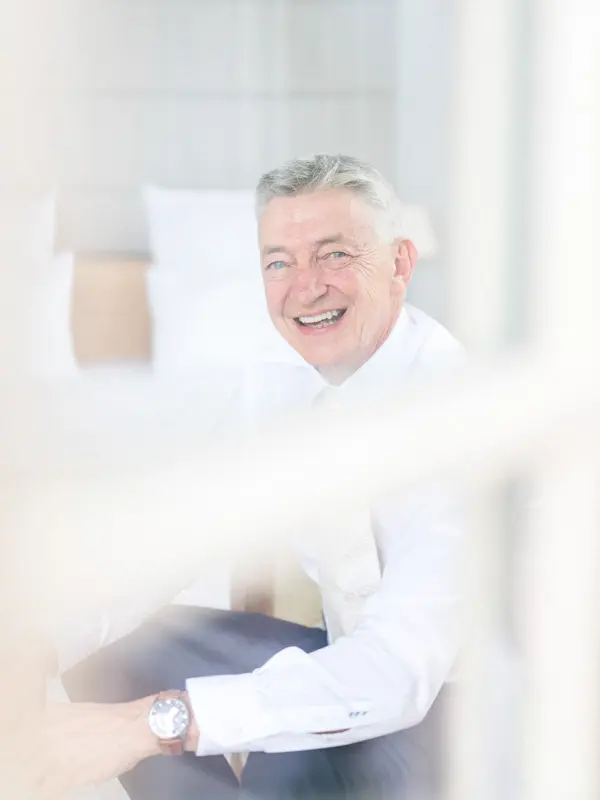 The smiling groom in a white shirt getting ready at the villa