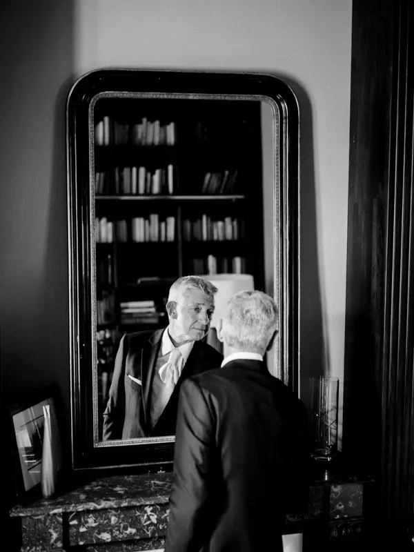 The groom reflected in a large antique library mirror, in black and white