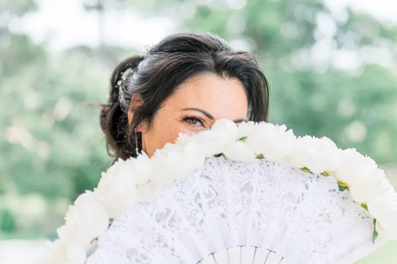 The bride hiding half her face behind her white lace fan