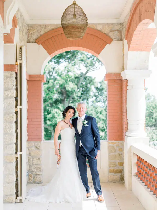 The bride and groom posing under the gallery arches of Villa la Tosca