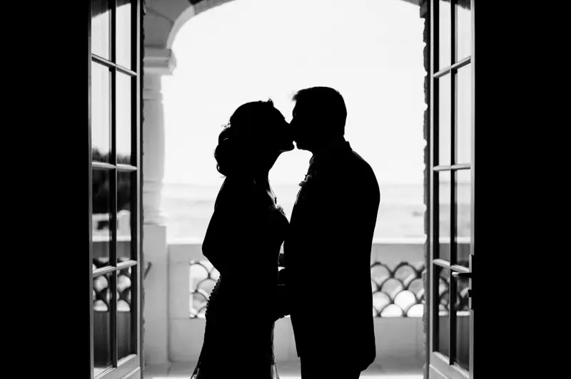 Silhouette of the couple kissing in front of a French window, in black and white