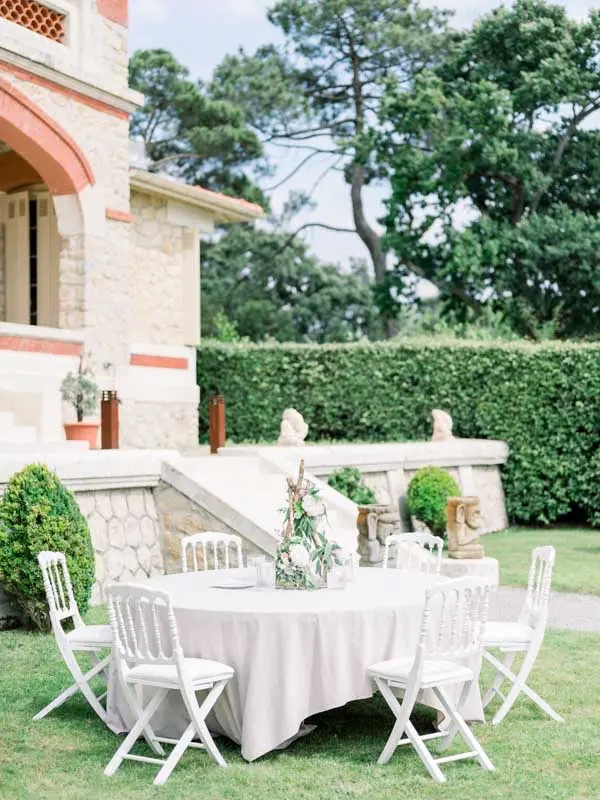 Round table with white linen and folding chairs in the villa garden