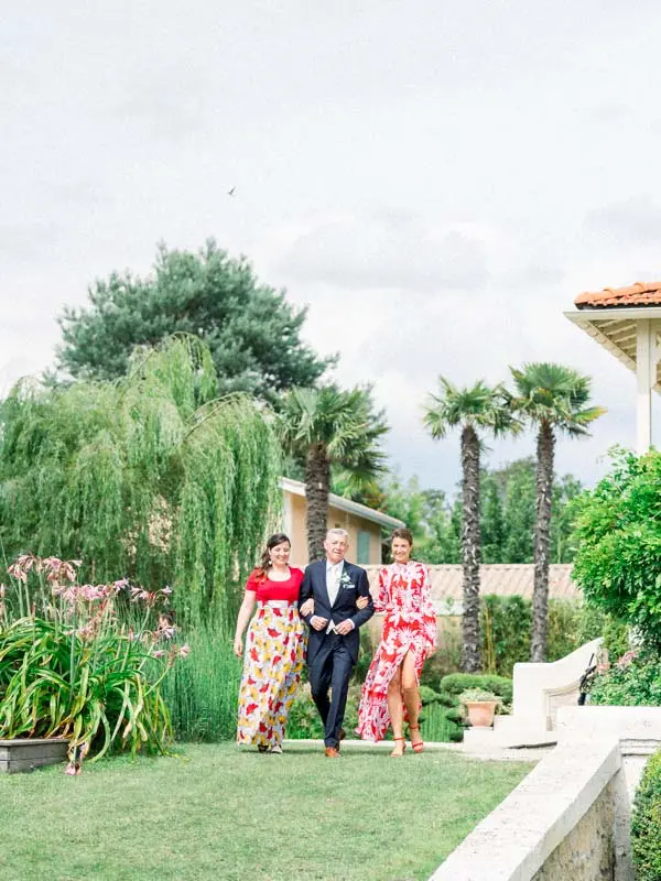 The wedding party walking through the garden toward the outdoor ceremony