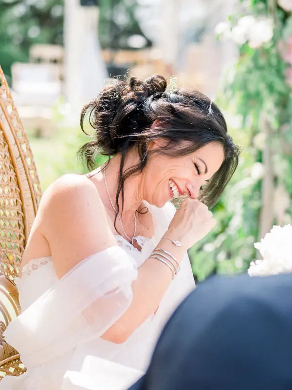 The bride wiping away a tear during the outdoor ceremony