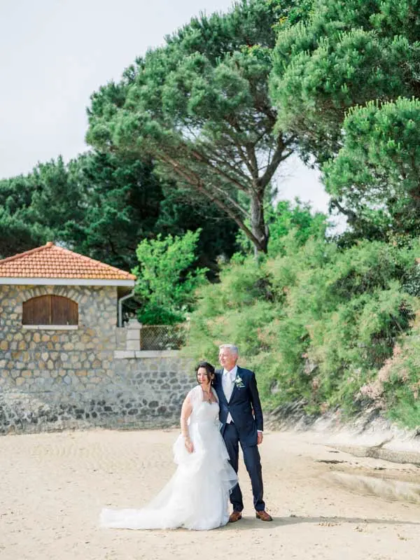 The bride and groom on the villa's beach beside the little stone house