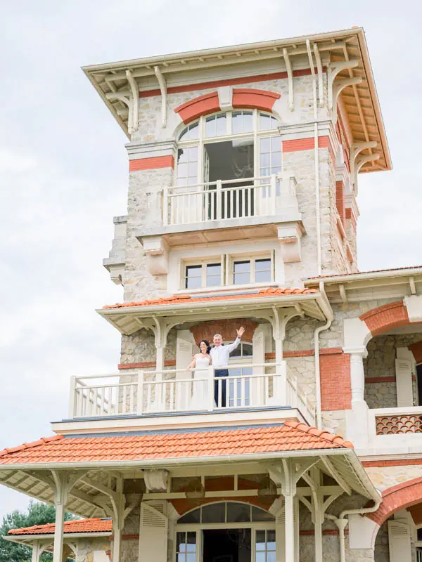 The bride and groom waving from the tower balcony of Villa la Tosca