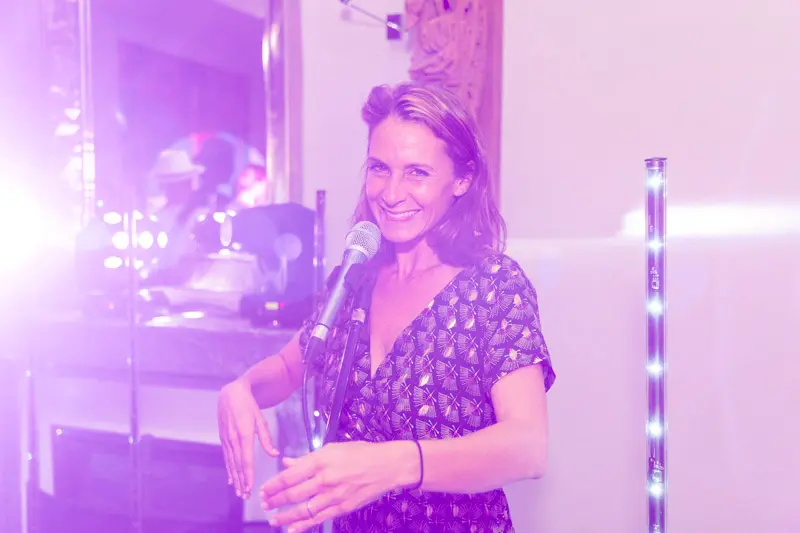 A singer in a floral dress under purple lights during the evening party