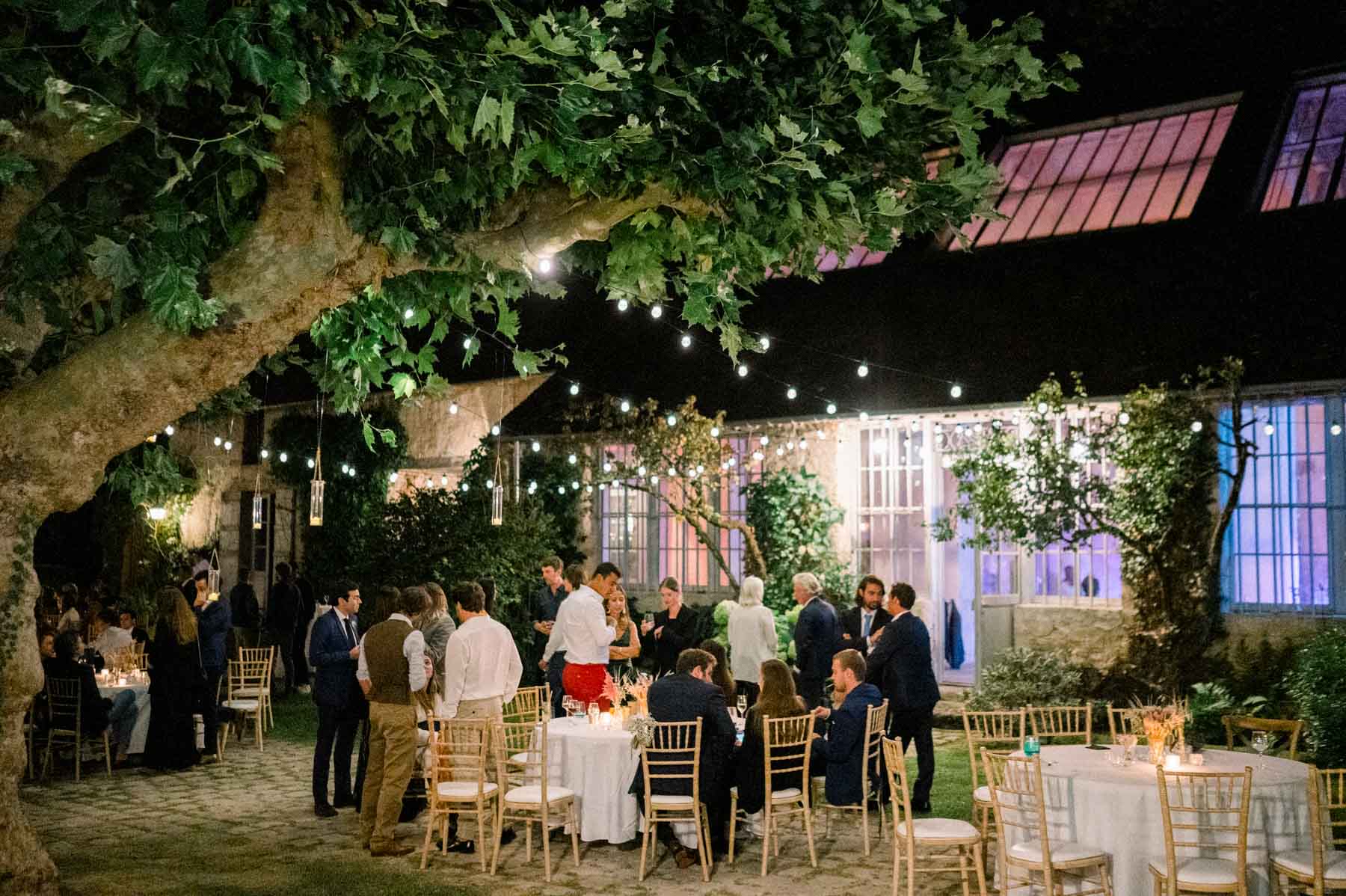Wedding evening with tables set beneath the trees and string lights