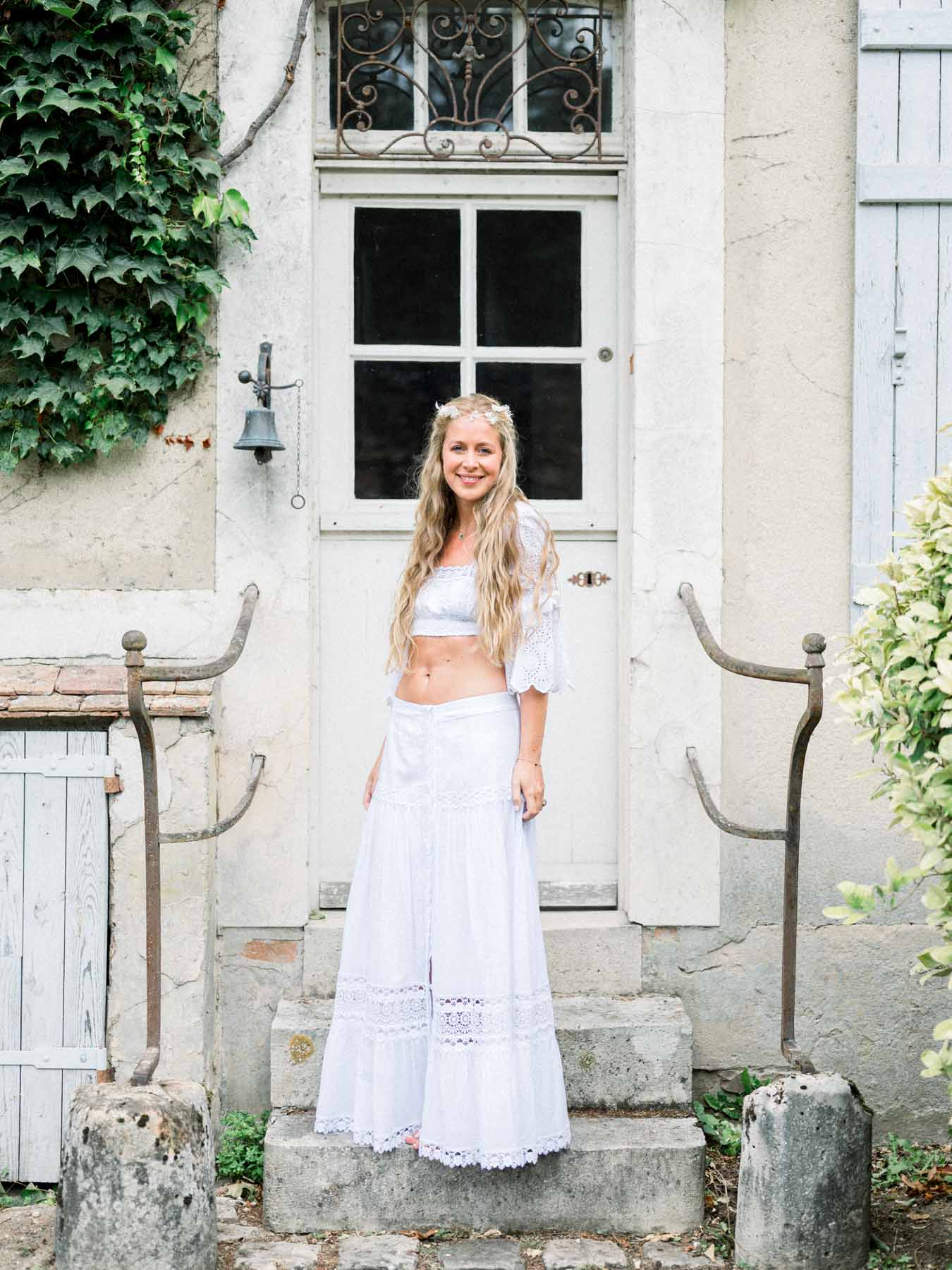 The bride in a white boho outfit at a stone doorway the day after