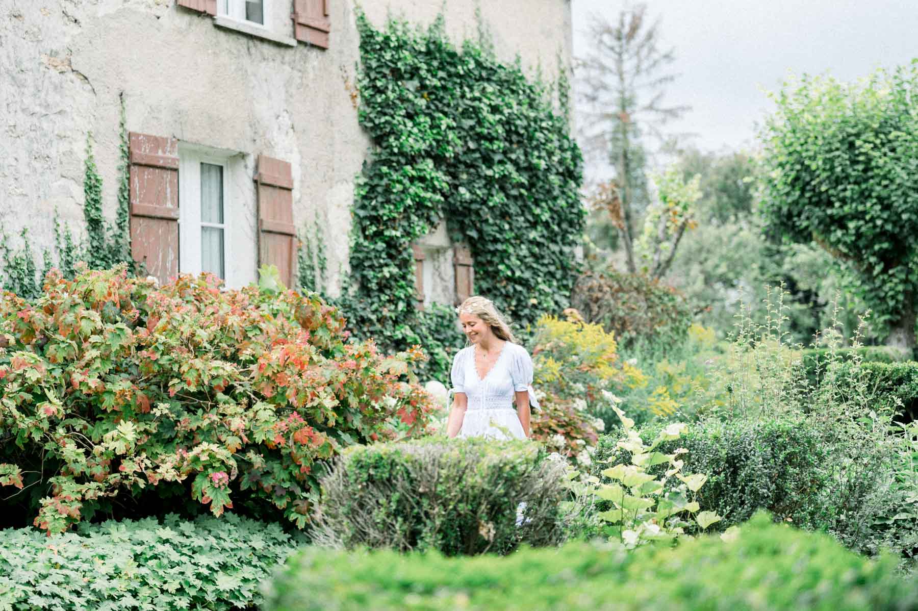The bride in a white dress amid the flowerbeds of the garden