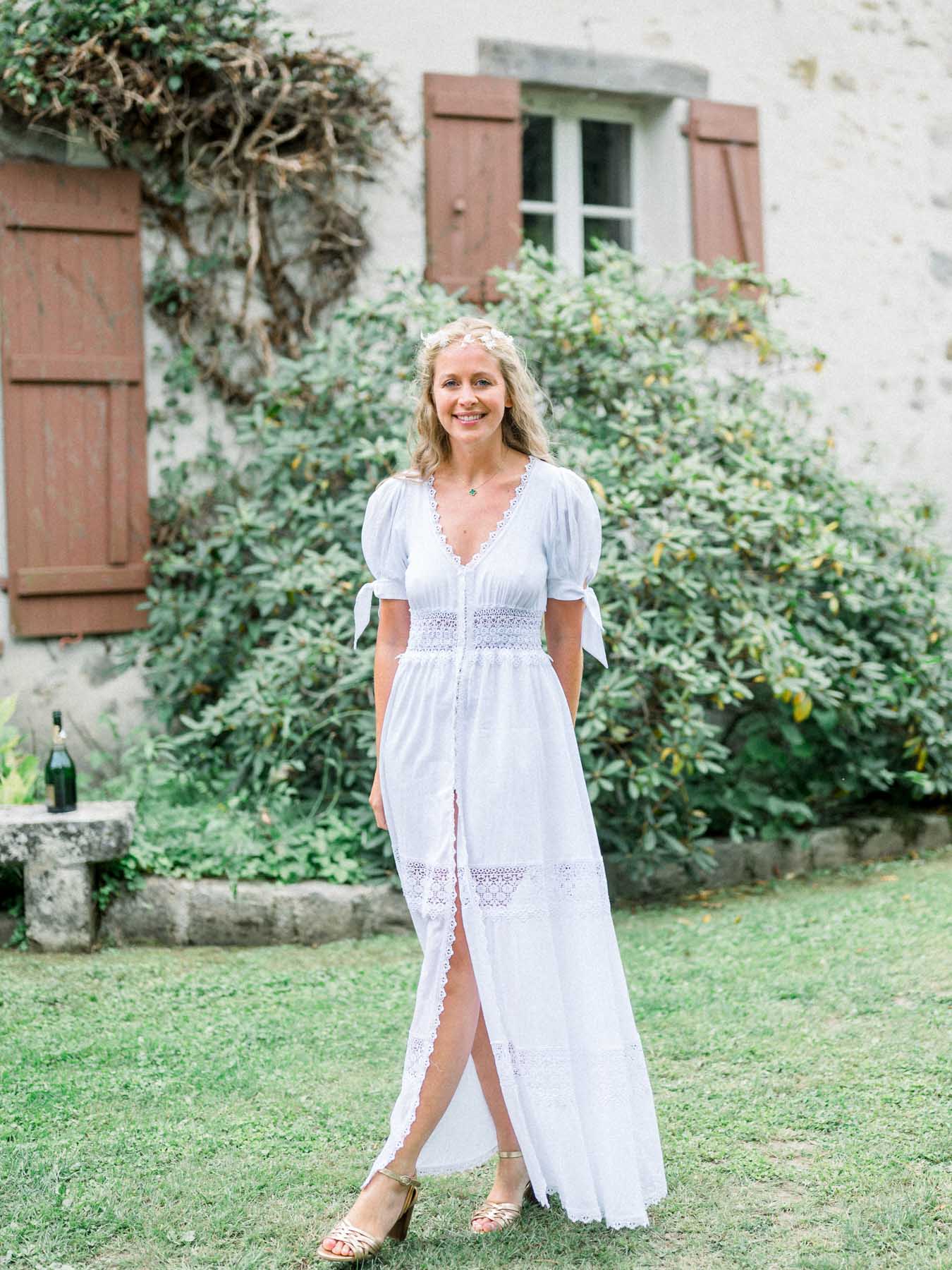 The bride in a long boho dress before a façade with brown shutters