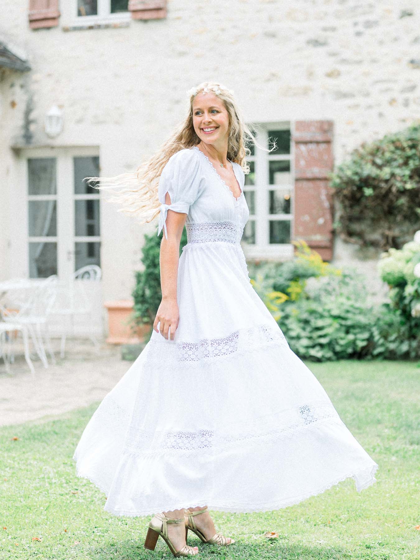 The bride twirling in her white boho dress on the lawn