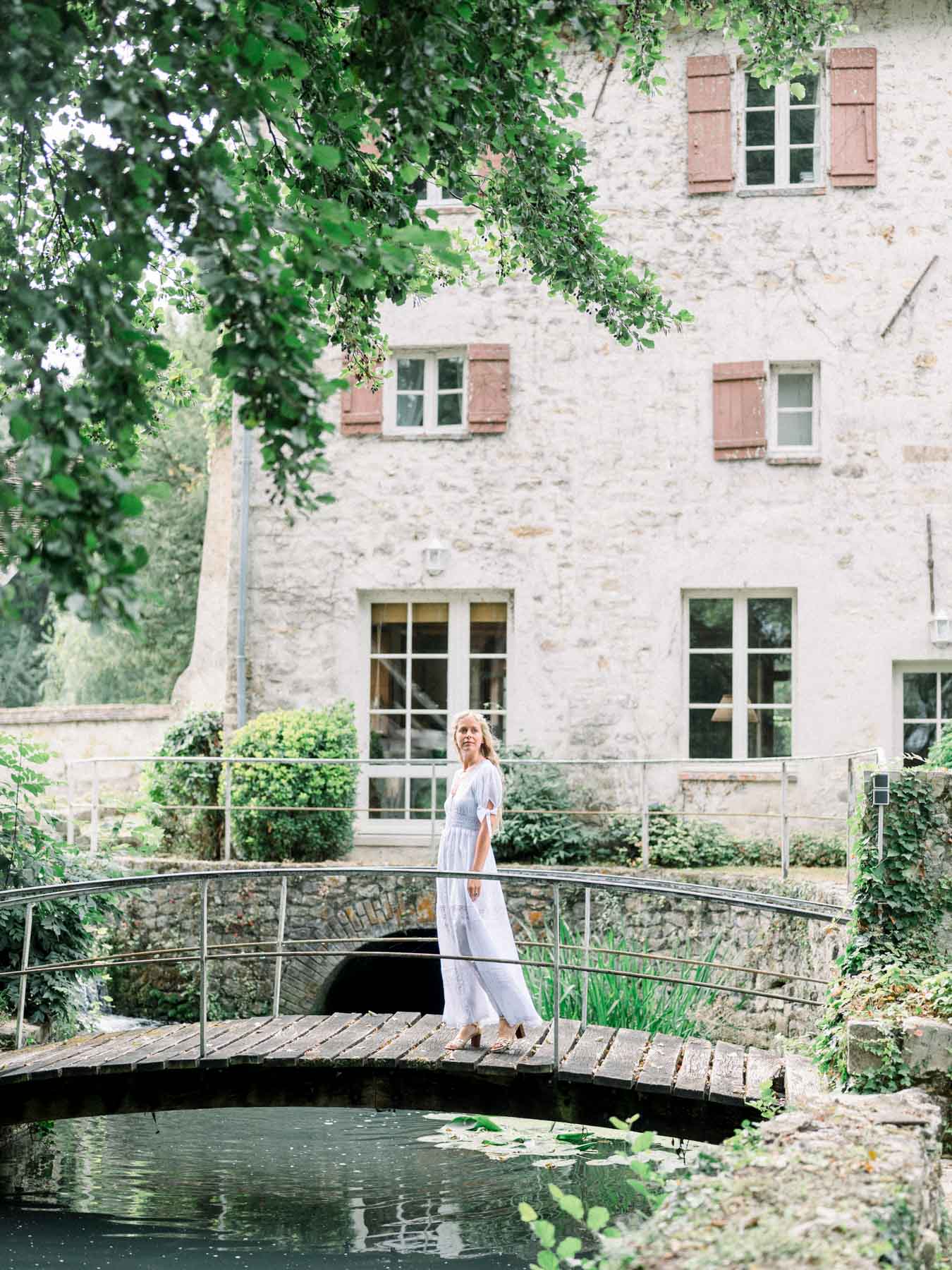 The bride on a small stone bridge over the water, in front of the house