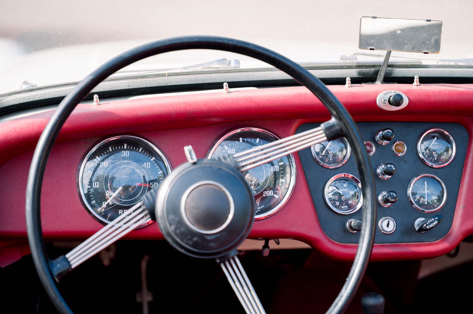 Red dashboard and steering wheel of the couple's vintage Triumph
