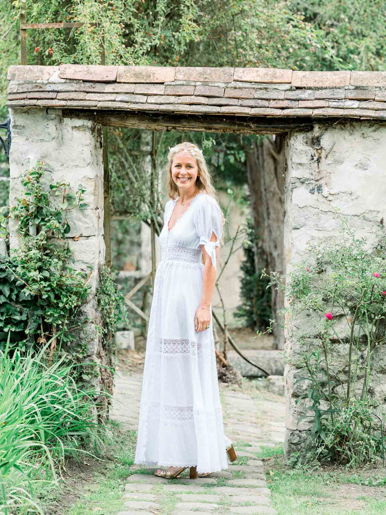 The bride beneath an overgrown stone pergola at Moulin de Launoy
