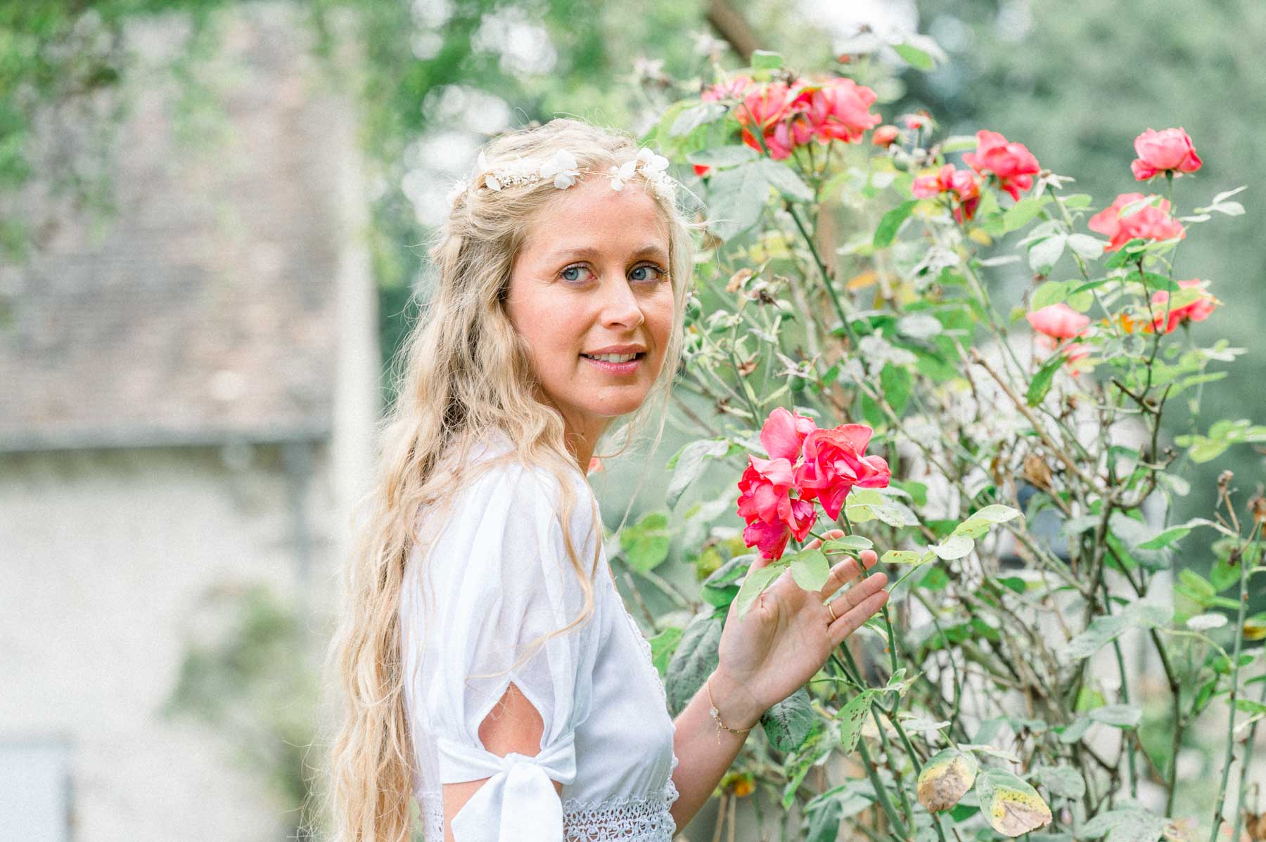 The bride touching red roses in the mill garden