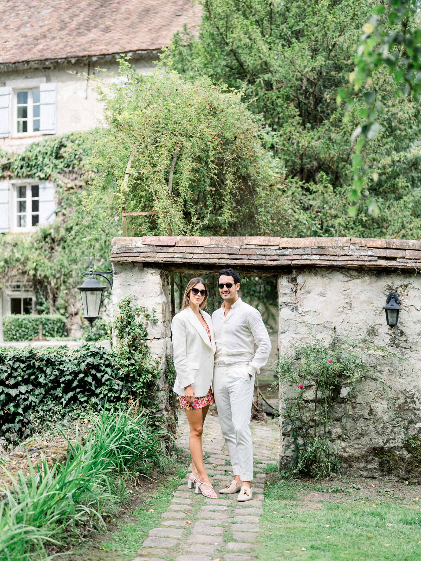 Guests dressed in white beneath a stone porch the day after the wedding